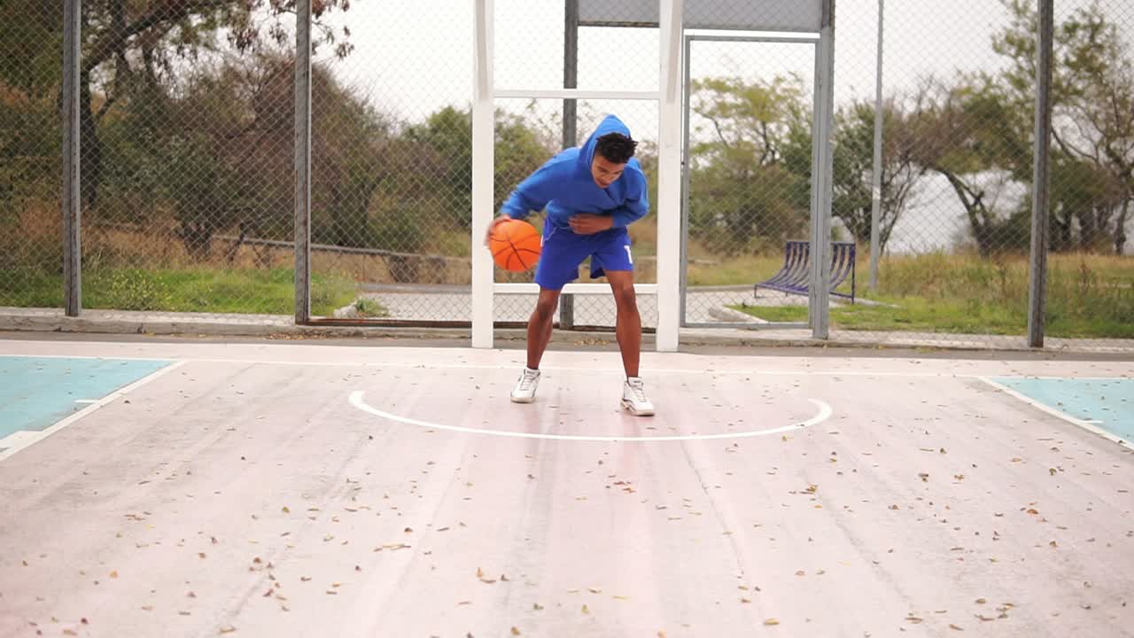 joven afroamericano practicando baloncesto afuera. disparo en cámara lenta