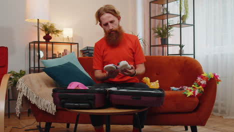 happy bearded man tourist packing suitcase luggage, preparation for vacation trip journey at sea