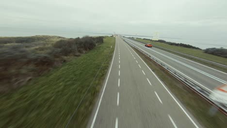 Drone-following-a-car-onto-the-stormsurge-barrier-bridge-in-the-Netherlands