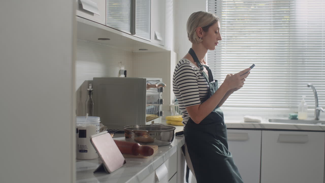 Housewife Using Smartphone at Home Kitchen