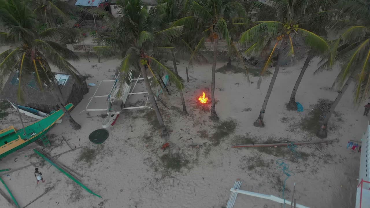 Vista aérea da Praia de Diapela com fogueira, barcos e pessoas ao belo pôr do sol em El Nido, Palawan, Filipinas