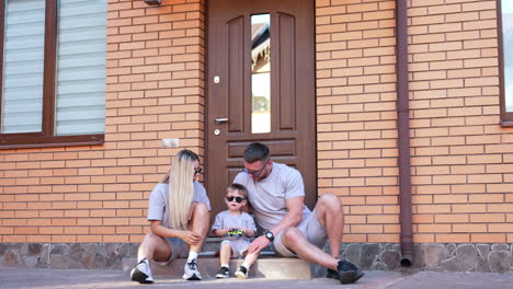 family enjoys time at home. family sits on steps at home, enjoying moments together while the child plays attentively with a toy
