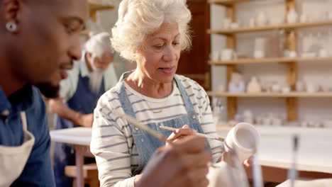 Dos-Alfareros-Diversos,-Masculinos-Y-Femeninos,-Vidriando-Una-Jarra-De-Arcilla-Y-Discutiendo-En-Un-Estudio-De-Cerámica,-En-Cámara-Lenta