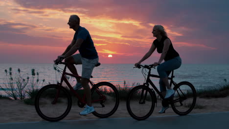 couple cycling silhouettes at sunset by the ocean