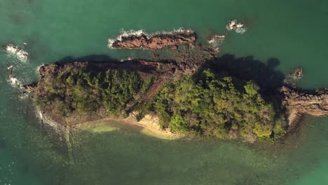 aerial-ascending-birds-eye-view-of-small-tropical-Island-with-beach-and-rocky-coastline