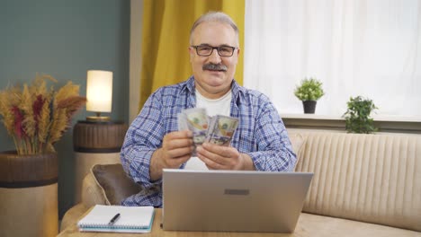 Man-looking-at-laptop-counting-money.