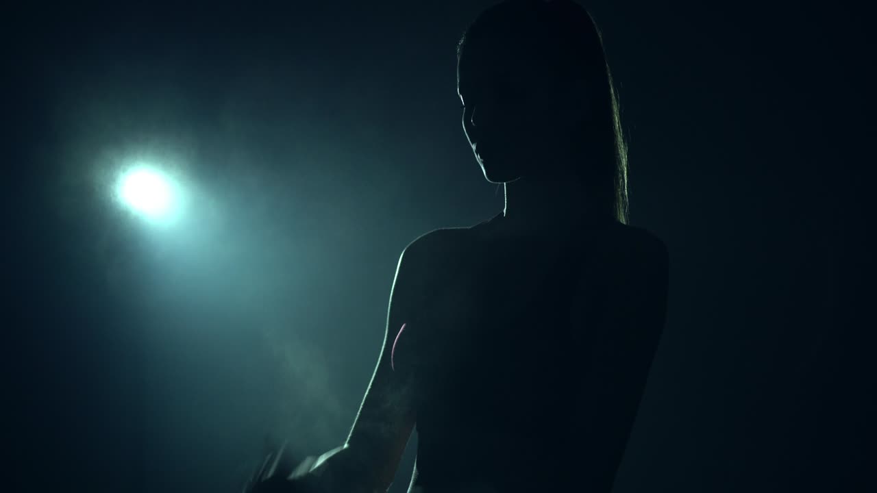 The young woman preparing for taking heavy barbell in the dark room