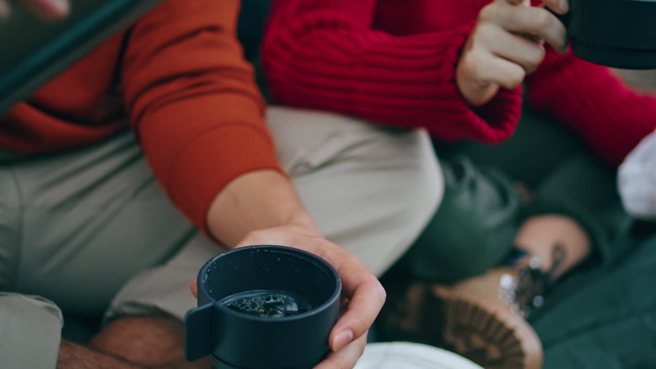 manos vertiendo bebida termo a la taza vertical de cerca. hombre desconocido llenando taza