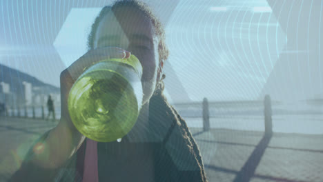 hexagonal shapes against african american woman drinking water on promenade