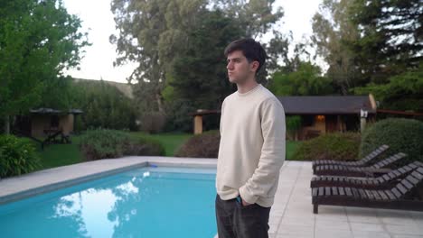 man looking afar standing by the swimming pool