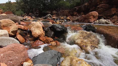 close up of the swollen spring runoff from oak creek rushes over rocks and boulders in the creek bed, sedona, arizona.