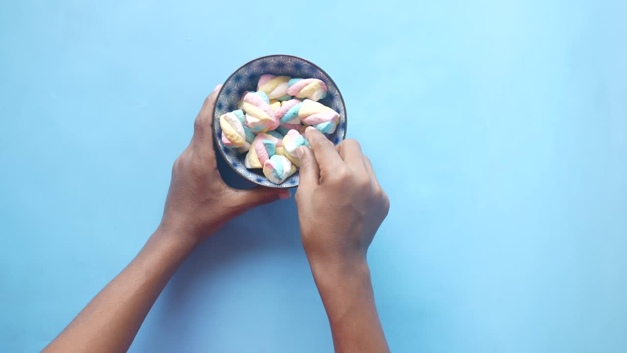 manos sosteniendo un cuenco de malvaviscos coloridos