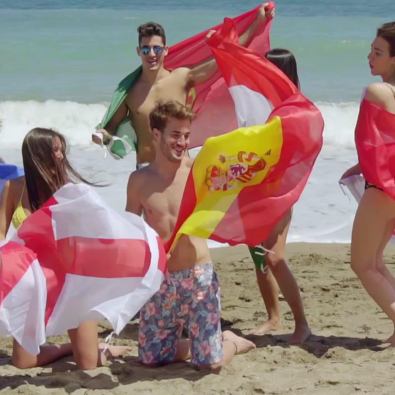 grupo de amigos en trajes de baño con banderas en la playa