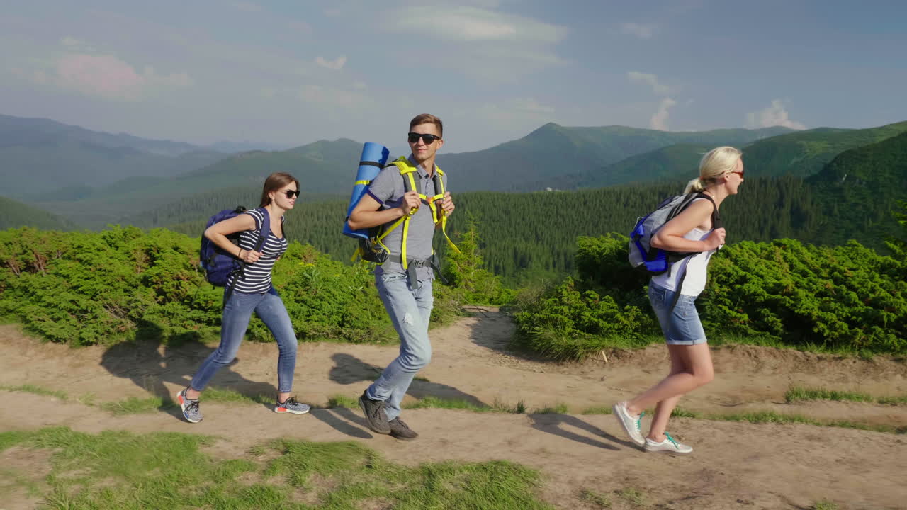 한 무리의 여행자들이 아름다운 산을 배경으로 산으로 올라간다