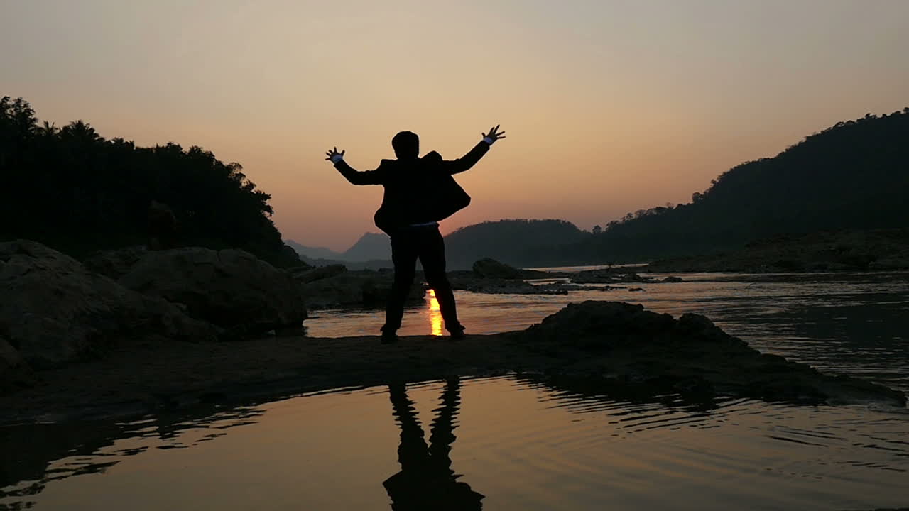 Silhouette of a Man at Sunset by the River