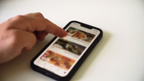 La-Foto-De-La-Mano-De-Un-Hombre-Desplazándose-Por-La-Aplicación-De-Pedidos-De-Comida-En-Un-Teléfono-Inteligente-Para-Elegir-La-Comida-Para-La-Cena