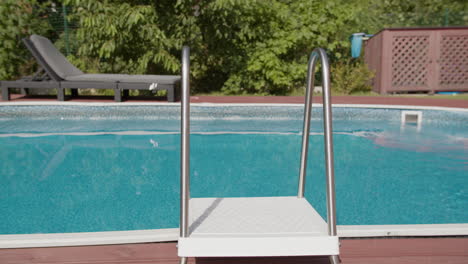 escena relajante de la piscina: una vista de una piscina con una escalera y chaise lounge