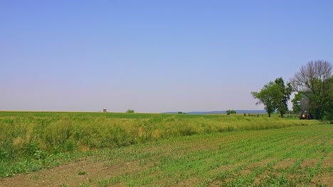 Eine-Restaurierte-Dampfmaschine-Und-Ein-Zug-Nähern-Sich-Und-Blasen-Rauch-Und-Dampf,-Die-An-Einem-Wolkenlosen-Tag-Durch-Die-Landschaft-Reisen