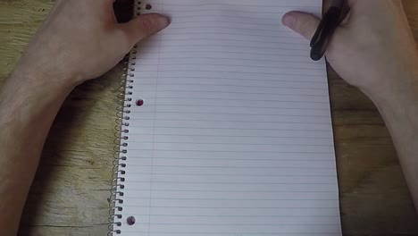 persona mirando un cuaderno de papel con un bolígrafo en la mano sin saber qué escribir