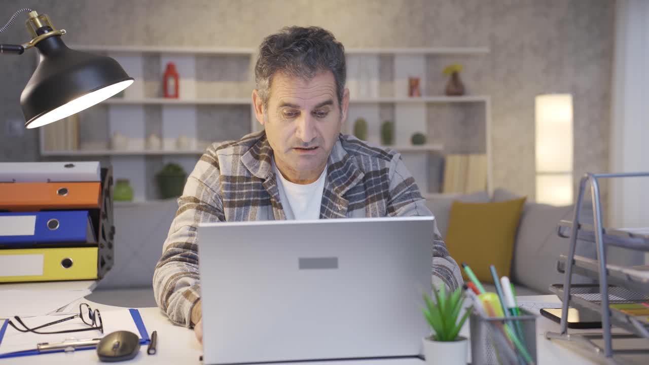 Mature man working in home office talking to himself about his work, making decisions and thinking.