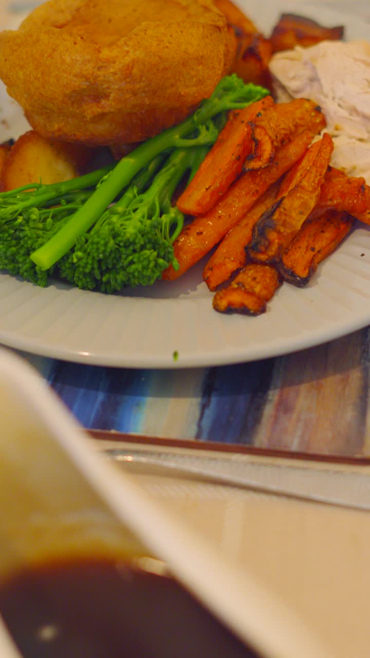 Vertical Video of Roast Dinner Setting with Gravy Jug with Freshly Roasted Carrots and Potatoes with Steamed Broccoli and Delicious Roast Chicken. Plated Food Photography.
