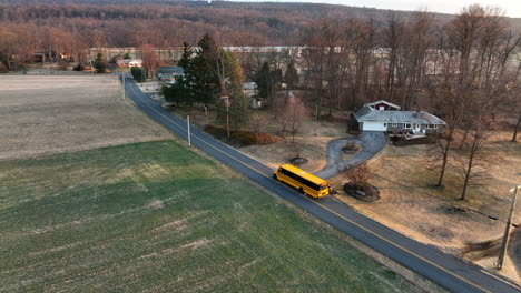 school bus drives on road through rural american countryside