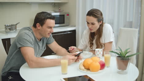 Smiling-couple-eating-breakfast-together-at-luxury-kitchen.