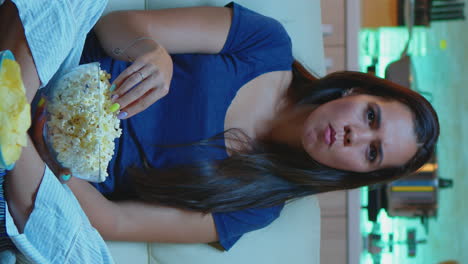 vertical video: person holding pop corn bowl watching movie