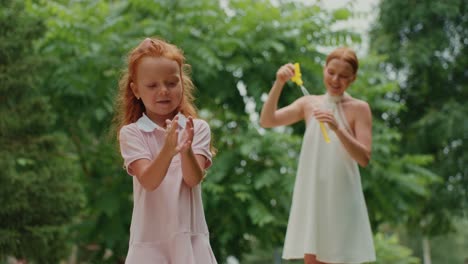 mother and daughter playing with bubbles in the park