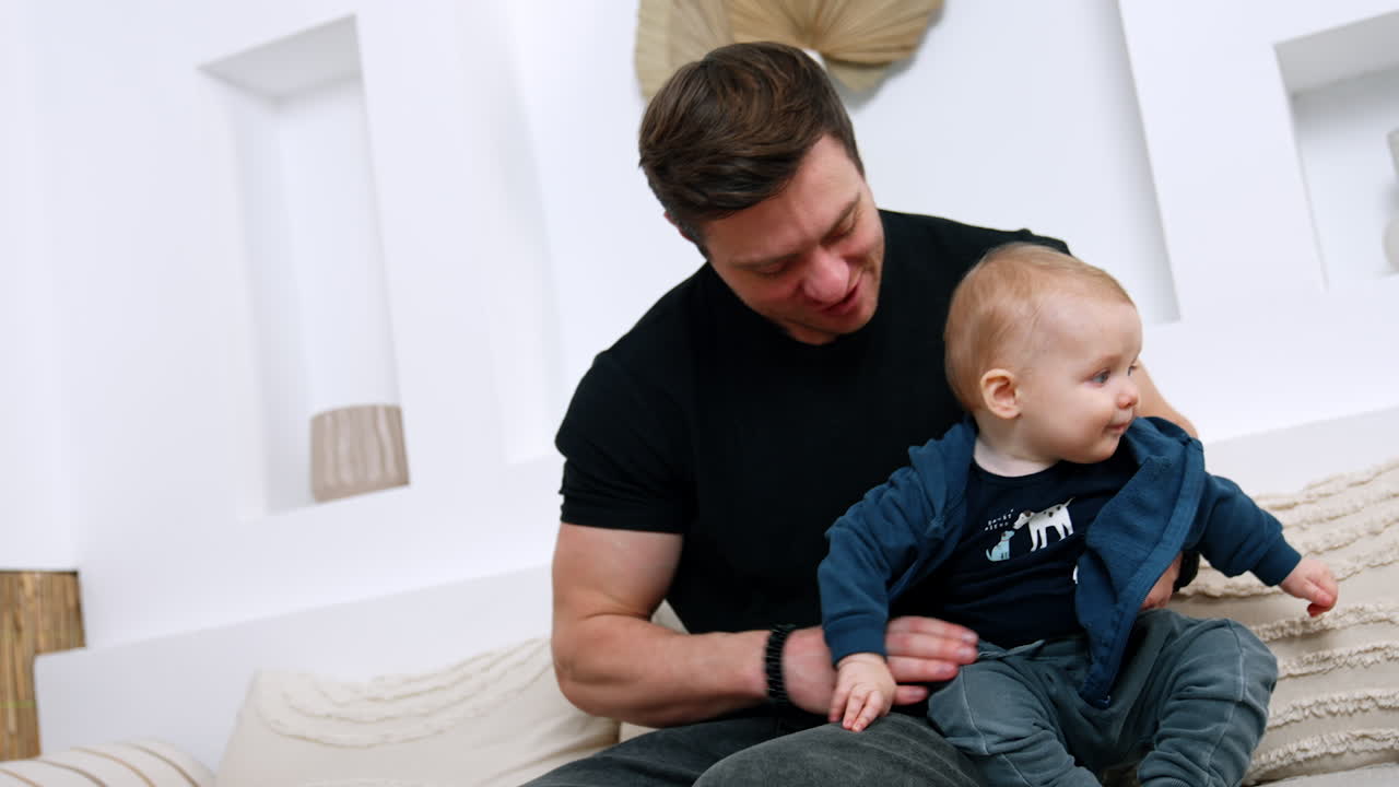 Loving Caucasian dad embracing his infant baby. Dad kisses beloved son on the cheek. Low angle view.