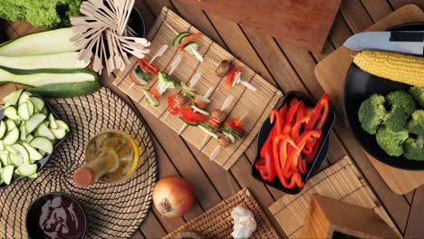 vegetable skewers lie on a wooden board surrounded by ingredients, static