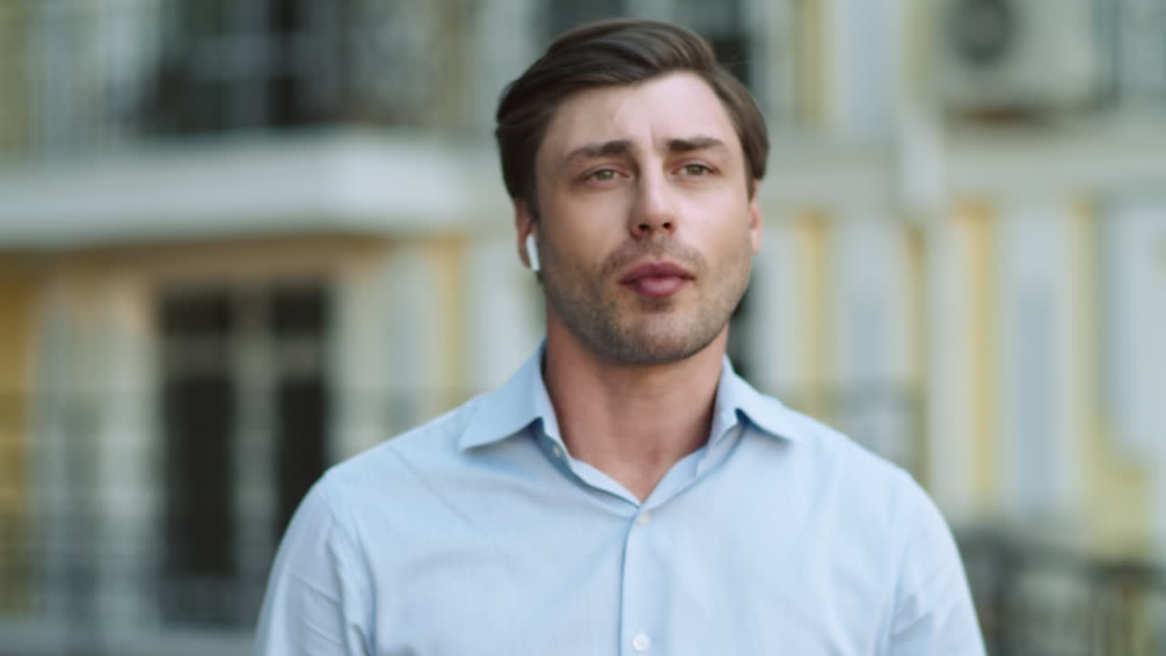 Portrait man walking with headphones at street. Man talking wireless earphones