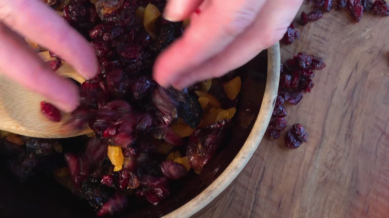 mexendo frutas secas de cores vivas em uma tigela grande para bolo de frutas