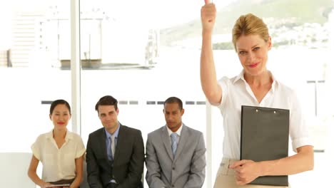 mujer de negocios dando pulgares a la cámara frente a los solicitantes de empleo