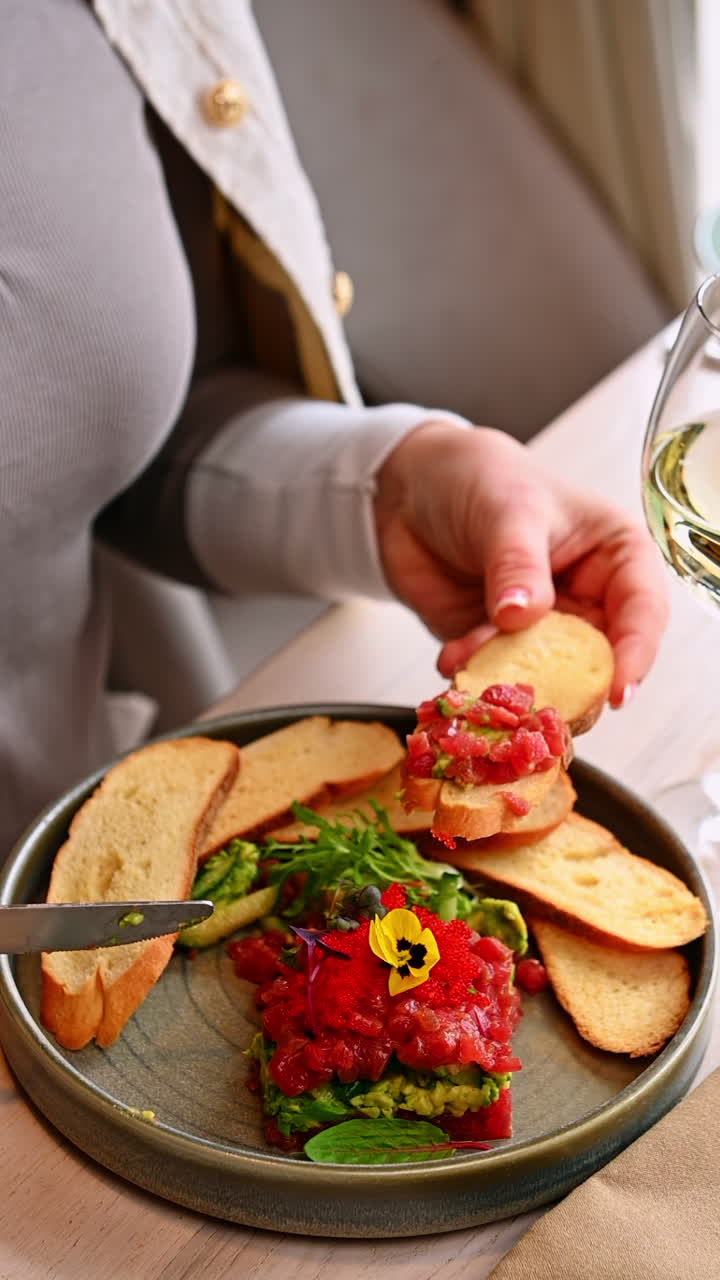 Glas vin med tunret. Hvidvinsglas i nærheden af farverig tatar med tun og avocado