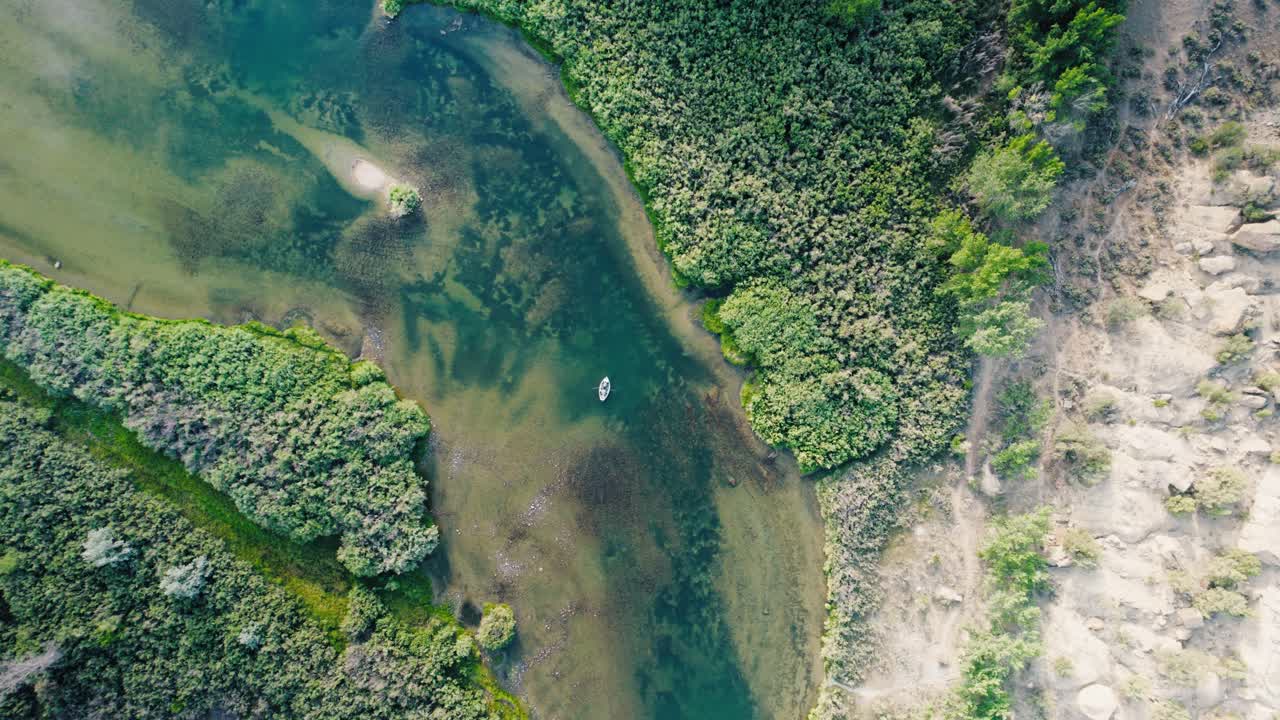 A high-altitude view showing the full scale of the San Juan river valley and the textures of the river beneath a guide boat.