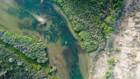 a high-altitude view showing the full scale of the san juan river valley and the textures of the river beneath a guide boat.