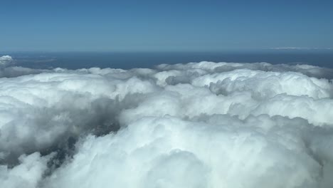 overflying some fluffy clouds during cruise, shot from a jet cabin at 5000m high