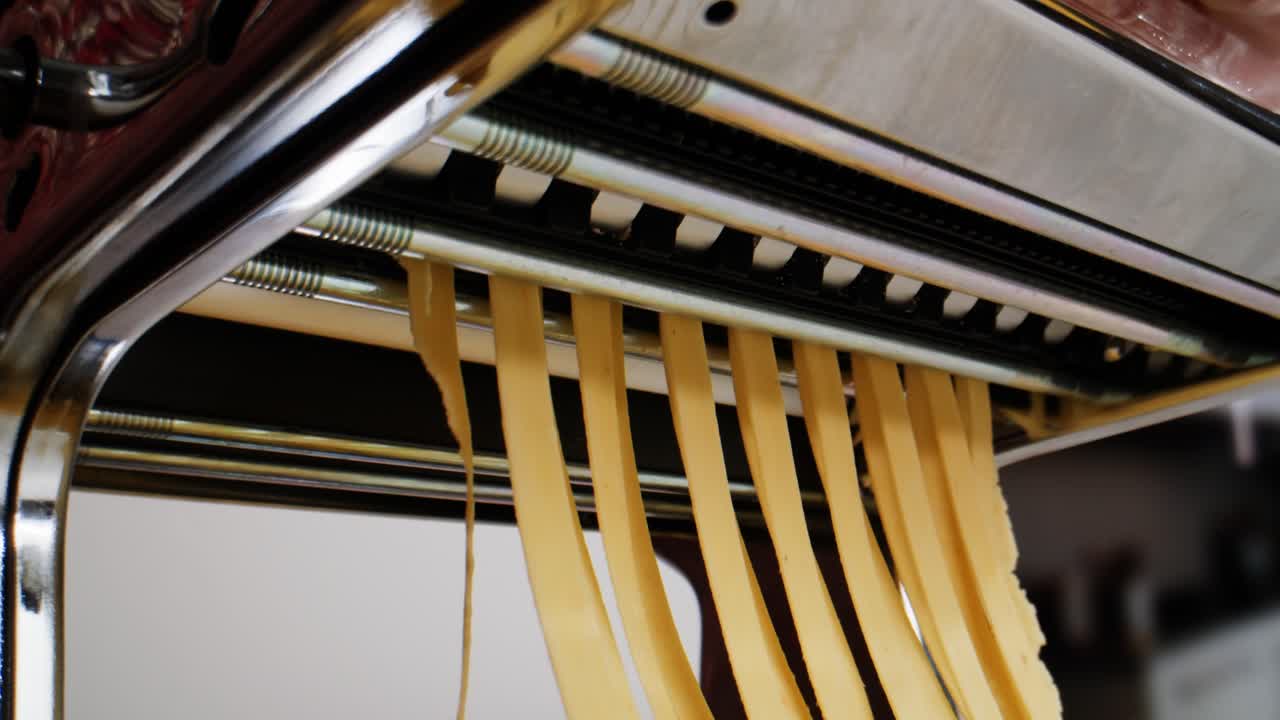 Fresh Pasta Dough Being Cut into Noodles by a Machine