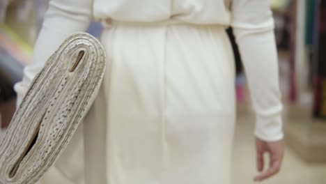 fashionable young woman in white clothes, walking through the textile store with fabric roll. white with polka dot printed. slow motion