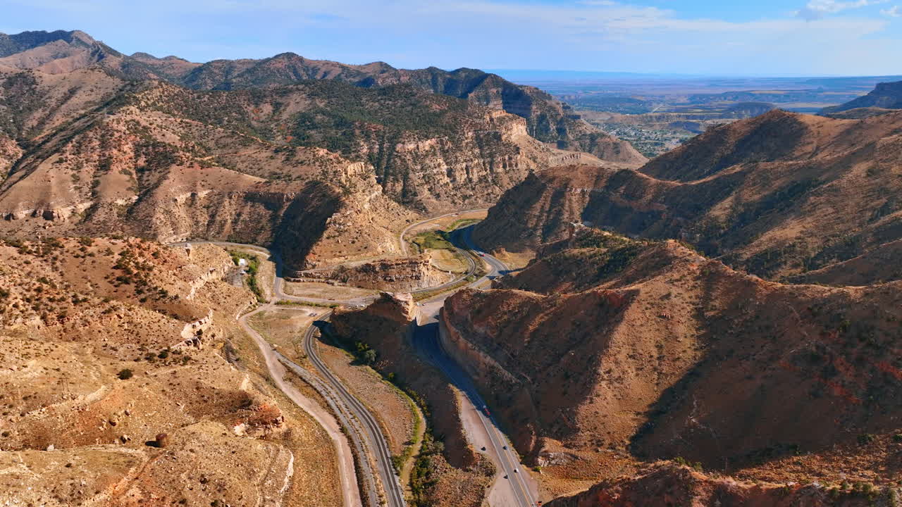 Aerial drone view of the highway cutting between the towering cliffs of Price Canyon in Utah under blue sky