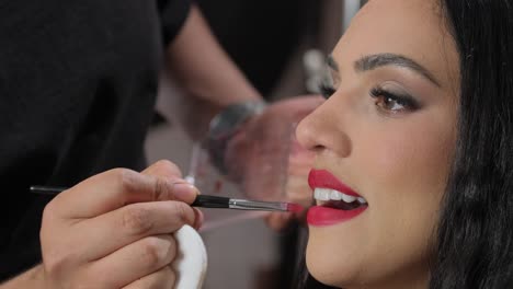 a skilled makeup artist carefully applies vibrant red lipstick, creating a flawless and stunning beauty look