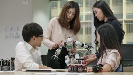 young asian creative engineers meeting, programming for collaborative universal robotics at laptop in workshop. people with technology or innovation concept.