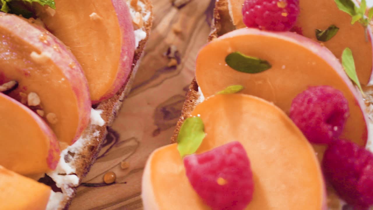 Peach ricotta toasts garnished with walnuts, fresh mint, and raspberries