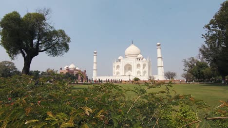 main facade of  taj maha, india. tourists walk at the gardens on sunny day