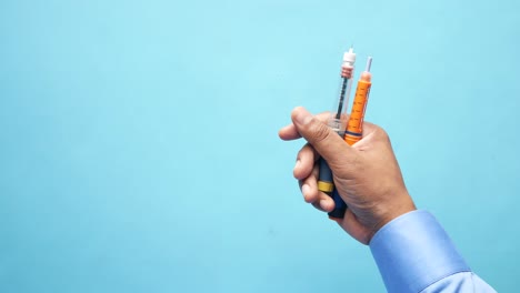 hand holding an insulin pen and syringe