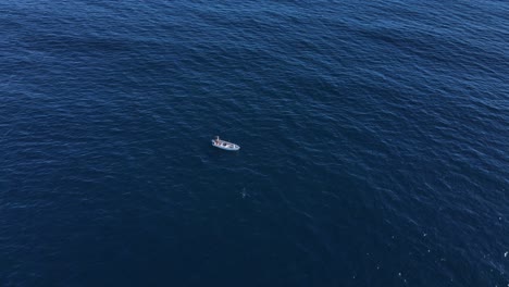 rising aerial view of lone fishing vessel in deep blue pacific open ocean water