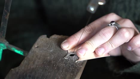 Cortar-Una-Pieza-De-Metal-Con-Precisión-Con-Una-Sierra-De-Marquetería-En-Un-Taller,-Primer-Plano