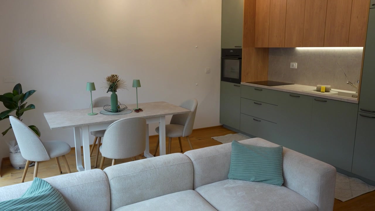 Filmato interno cinematografico di una casa accogliente e arredata, con cucina completamente attrezzata, tavolo da pranzo e comodo divano in un open space. Ideale per immobiliare, interior design, arredamento per la casa.