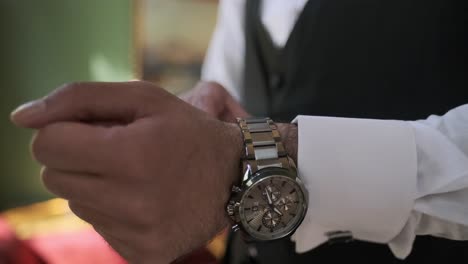 businessman dresses and someone adjusts his watch, preparing for a meeting